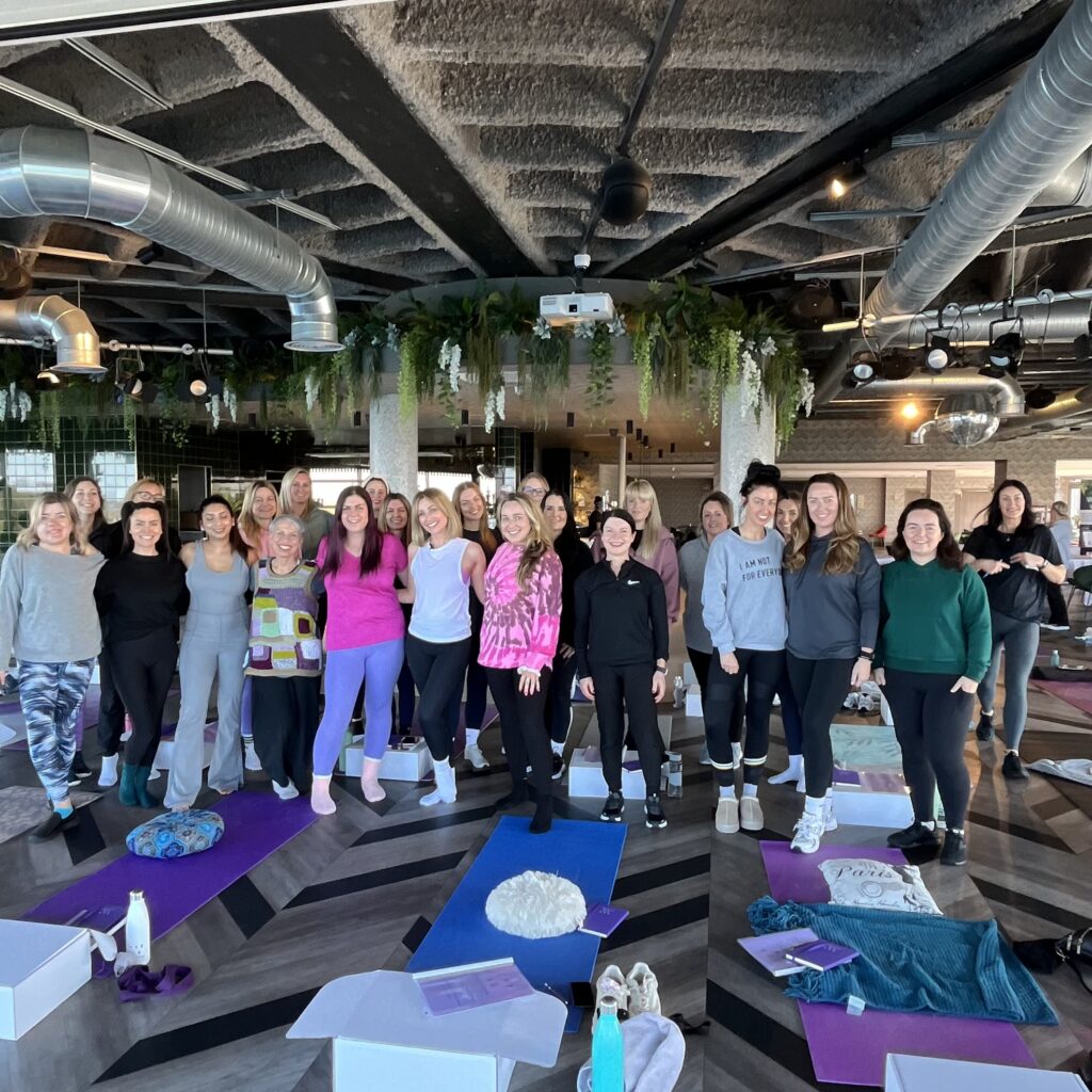 A group photo of 20+ smiling yoga session participants following a day with Gemma